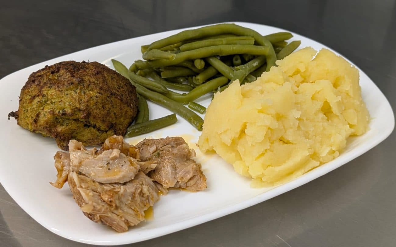 Assiette de galette de légumes, haricots verts entiers, purée lisse et viande en morceaux