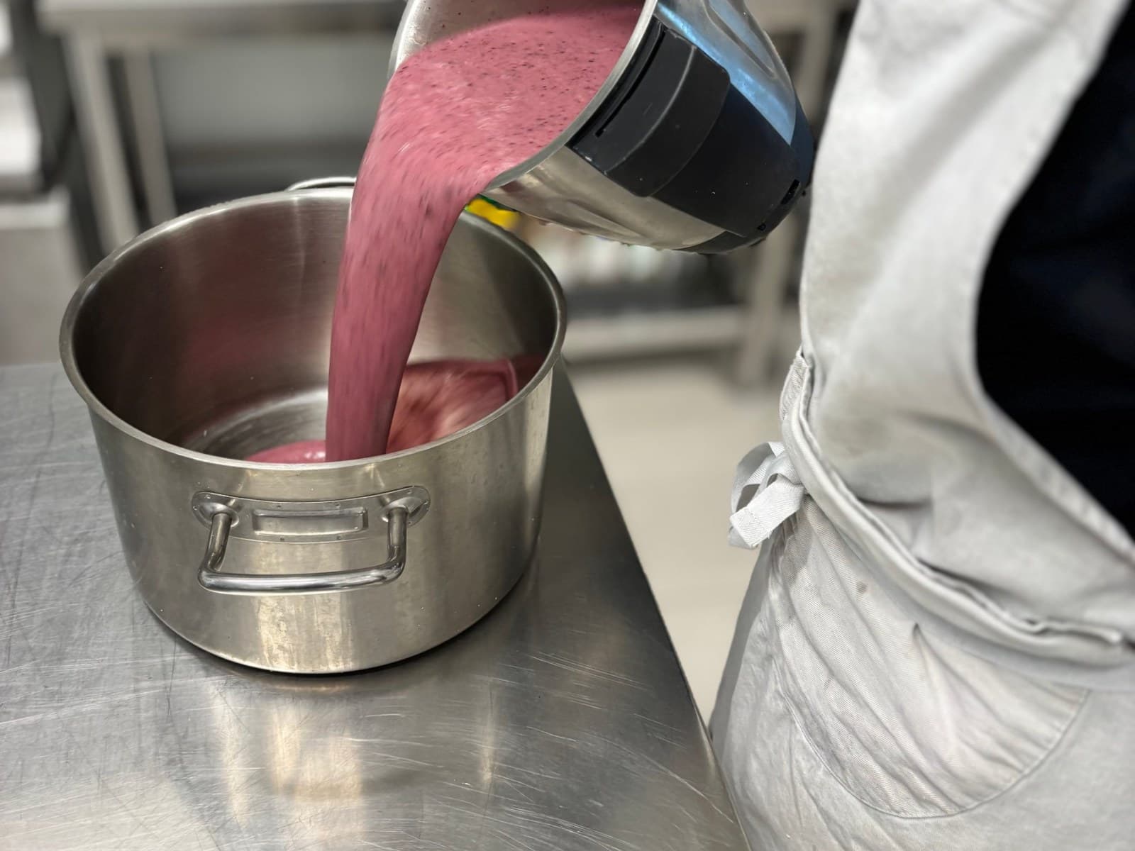 Purée de fruits rouges versée dans une casserole en cuisine